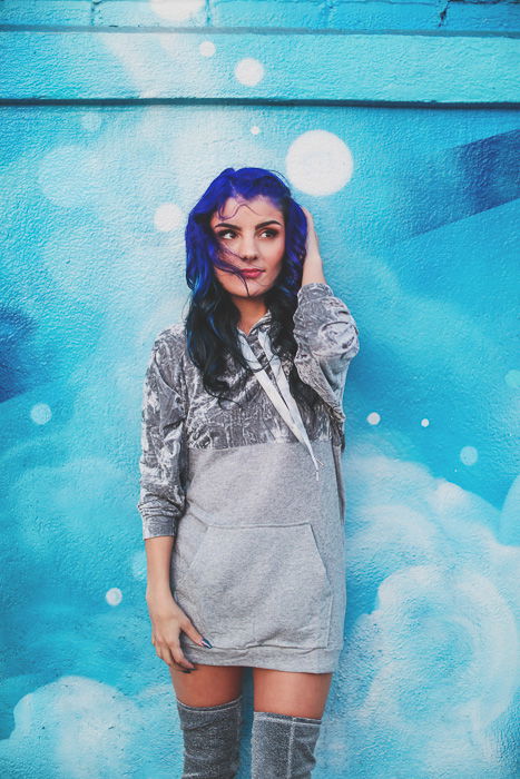 A stock photo of a blue haired female model posing in front of a blue wall