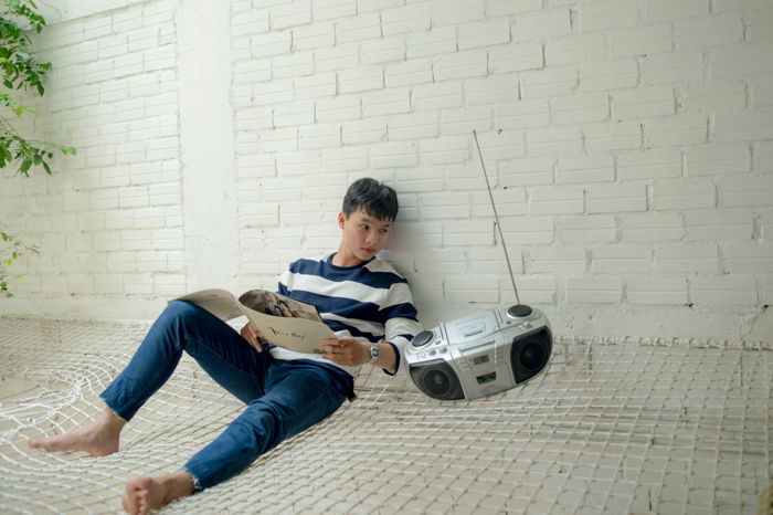 A badly edited stock photo of a man sitting beside a radio