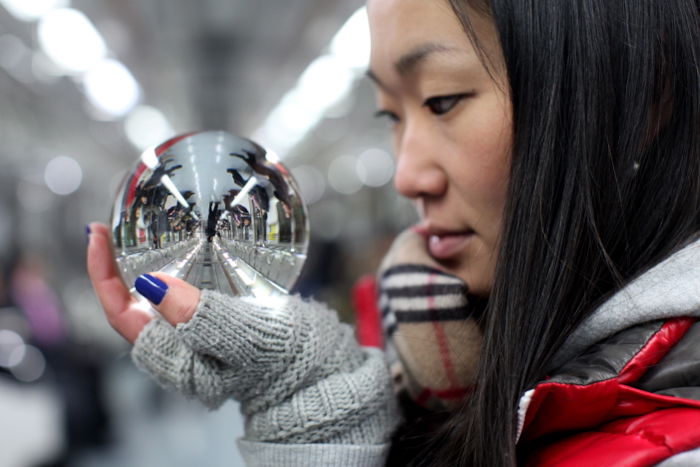 A portarit of a female model holding a crystal ball reflecting the interior of a train