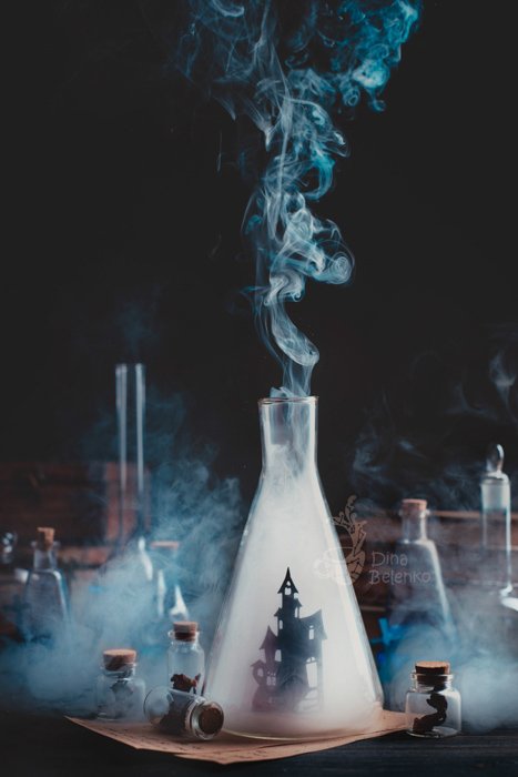 Atmospheric magic themed still life composition featuring glass bottles, smoke and test tubes