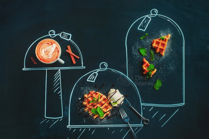 A still life flat lay of coffee, waffles and ingredients on a chalk hopscotch grid on a dark background 