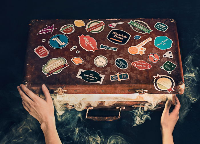 An overhead shot of a person opening an old suitcase covered with stickers - examples of using text in photography