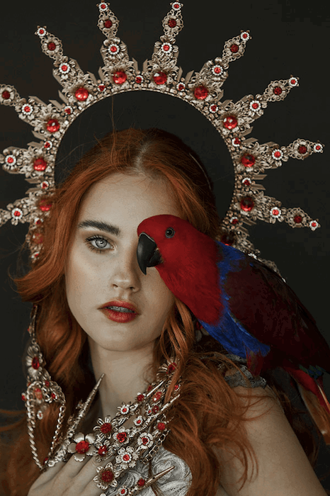 Fine art portrait with a parrot on the shoulder of a model wearing a crown 