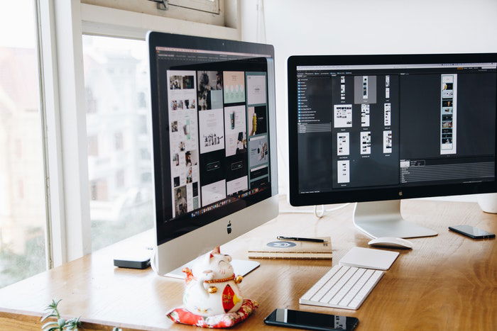 two Apple desktop computers on a trendy desk 