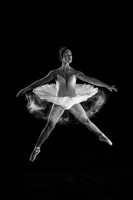 Artistic ballet photography shot of a female ballerina dancing onstage in low light