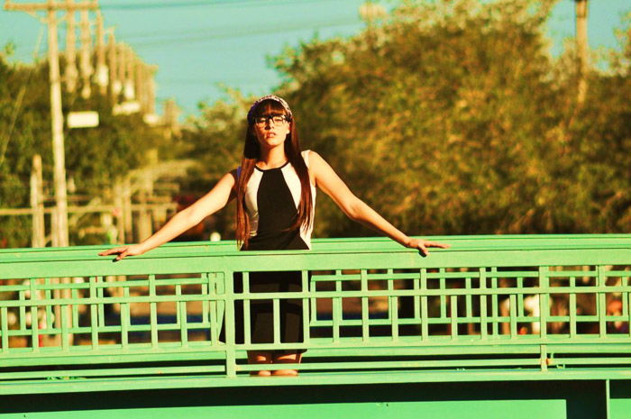 A portrait of a female model posing on a green bridge with long shot camera angles