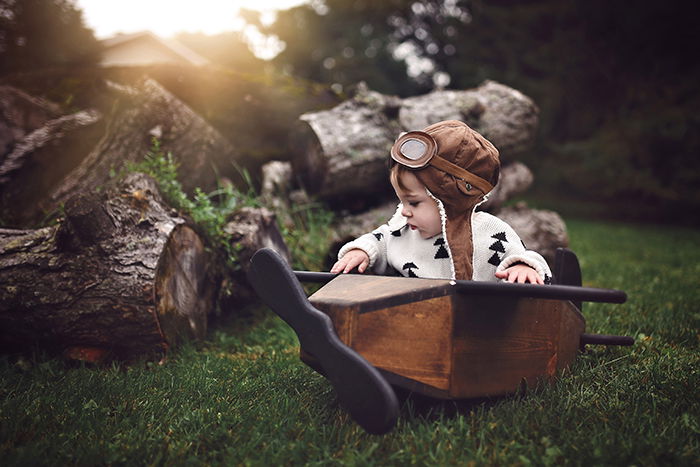 A conceptual photo of a young boy in a wooden boat outdoors