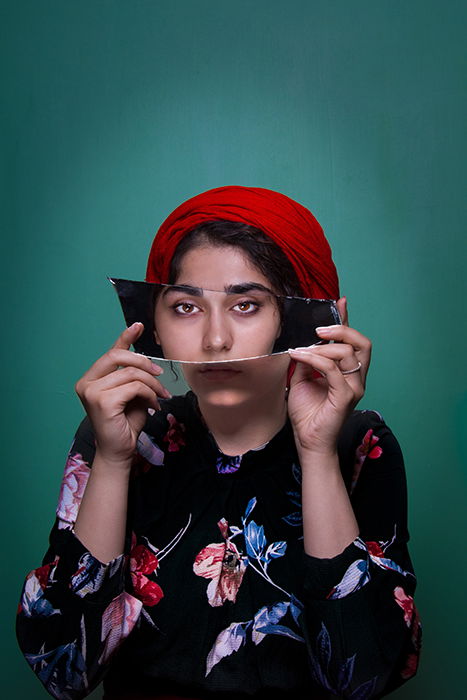 A colorful portrait of a female model holding a mirror to her face - conceptual photography ideas 