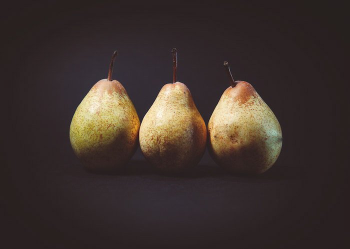 Three pears on a black background demonstrating the use of the rule of odds in food photography 