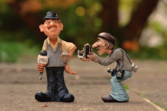 Figurines of a journalist taking a photograph of a television personality