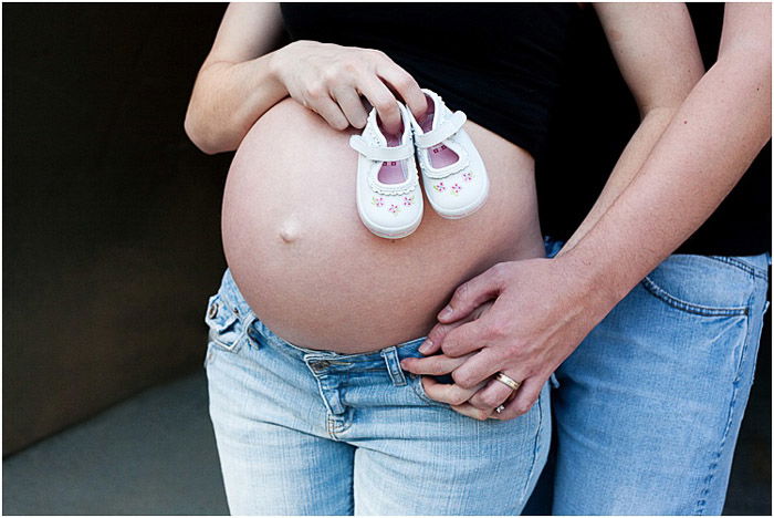 A maternity portrait close up of a man touching his partners pregnant belly