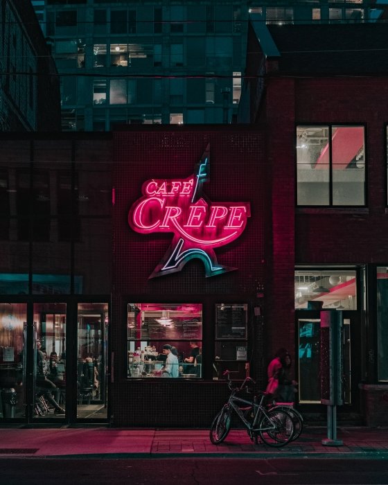 Neon 'cafe crepe' sign at night 