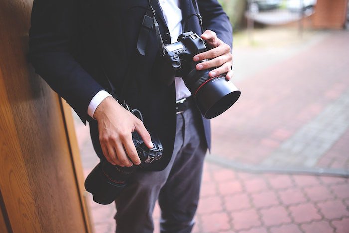 A close up of a professional photographer holding a DSLR at a photo shoot