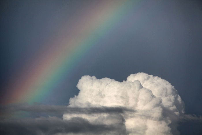 A stunning rainbow picture beside a white fluffy cloud