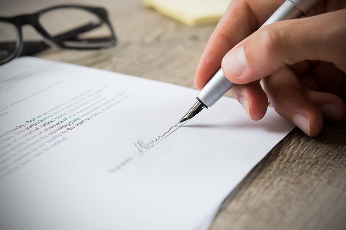 A close up of a photographer signing a contract to sell stock images to a major stock website