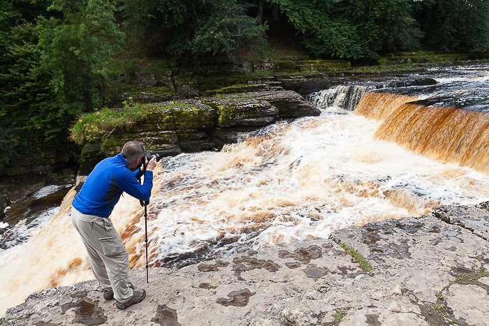 A photographer taking a shot of a waterfall - sell photos online
