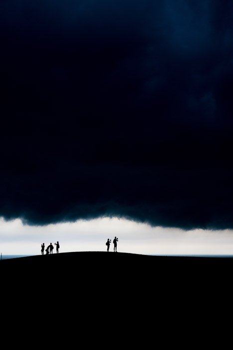 The silhouettes of people amongst a dramatic evening landscape 