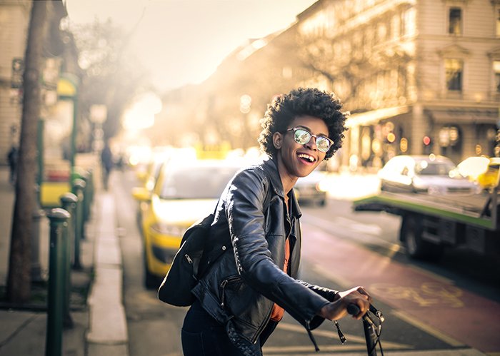 Tipos de fotografía de retrato - Retrato sincero de una chica en bicicleta en una calle concurrida de la ciudad
