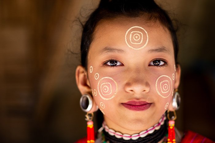 A close up portrait of a young Kayaw Girl in traditional dress and face paint - shallow vs deep depth of field