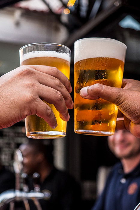 Beer photography shot of two people clinking glasses indoors