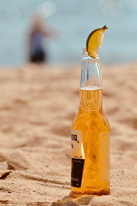 A bottle of corona beer with lime on a beach - how to photograph beer