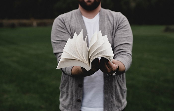 A man holding an open book in front of him. 