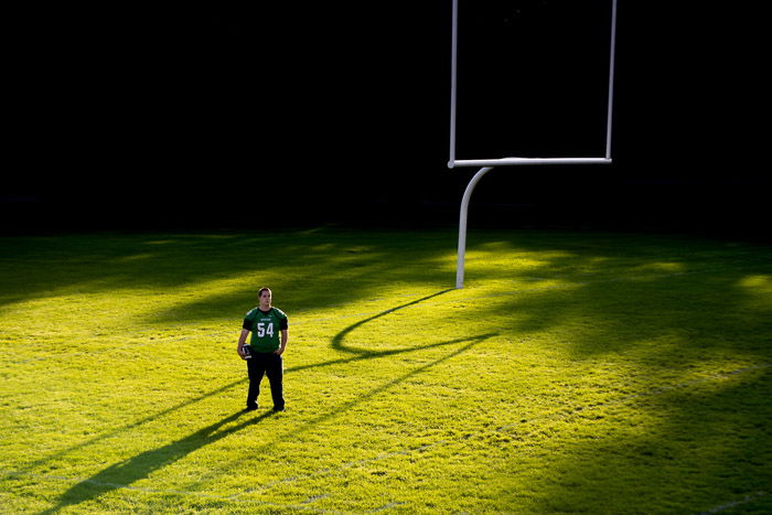 photo of a guy standing in the middle of a football pitch with dramatic lighting