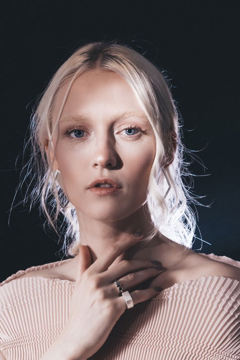 Dreamy backlit portrait of a female model posing against a black background