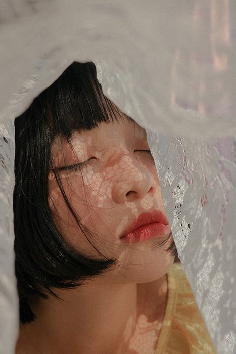 Retrato sonhador de um modelo feminino posando com cortinas de renda 