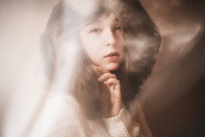 Dreamy portrait photo of a female model posing indoors in soft light
