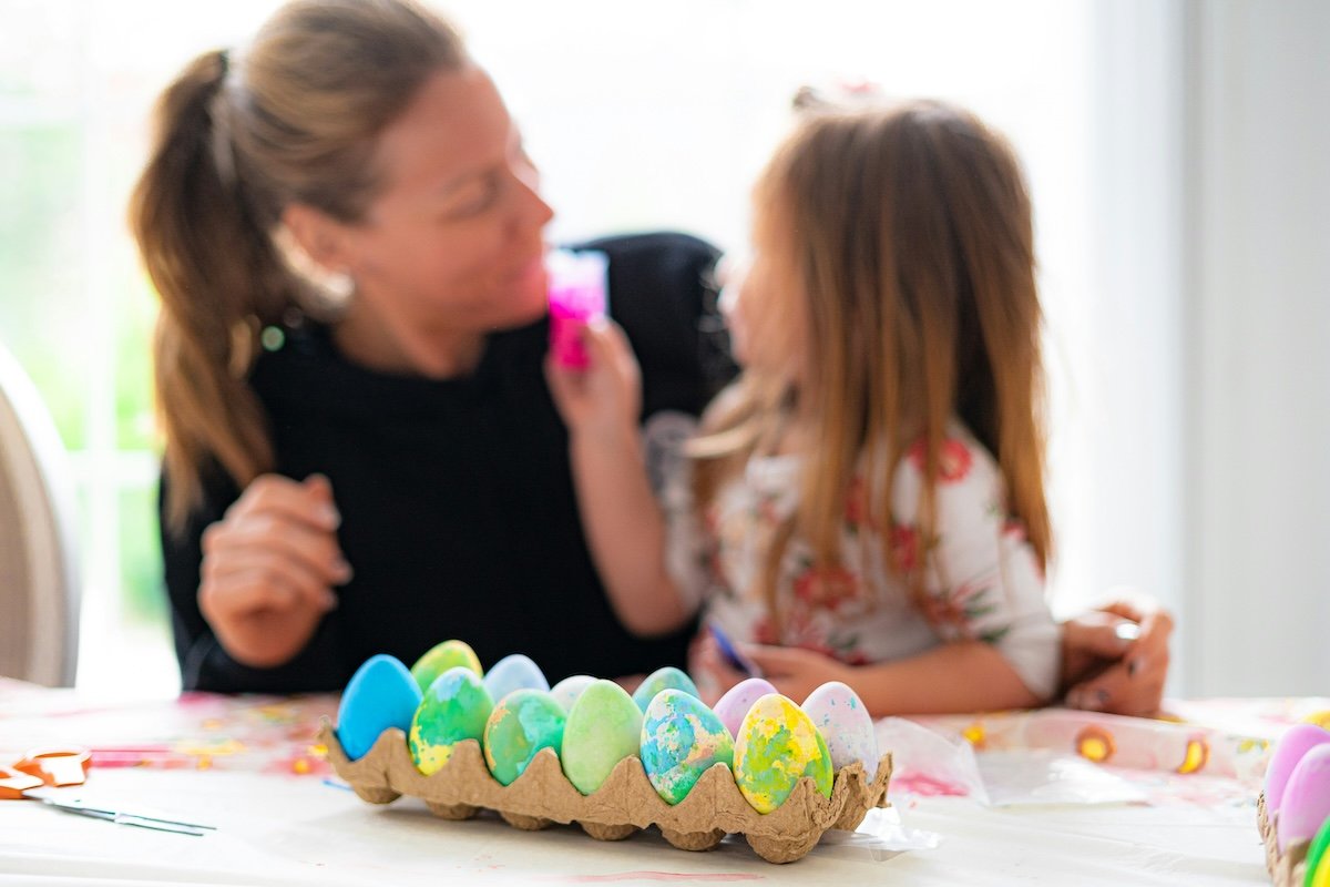 Decorated eggs with a mother an child in the background as an example of Easter picture ideas