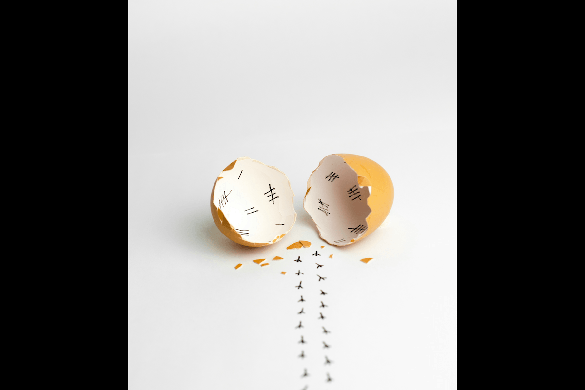 A unique funny composed conceptual still-life scene made from a cracked egg shell and ink as an example for Easter picture ideas