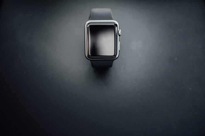 Overhead product shot of a black watch on a black background 