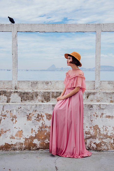 A female fashion model posing outdoors in vintage pink dress