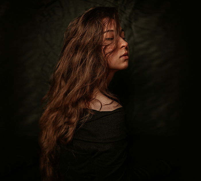Atmospheric self portrait of a female model posing against a black background - fine art photography mistakes