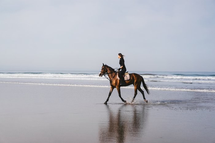 Picture of a woman riding a horse on a beach using the rule of thirds