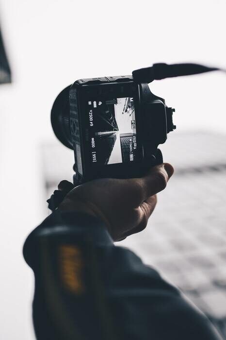 Black and white photo of a camera taking photo of a skyscraper