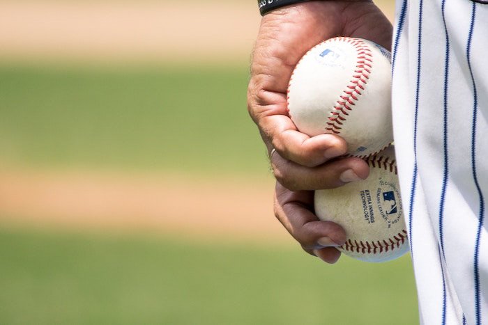 A close up of a baseball player holding two balls 