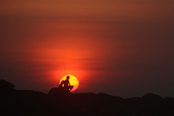 Silhouettes of two people sitting on rocks sunset - minimalist nature photography