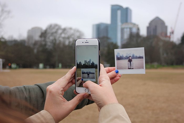 Close up shot of a person taking a photo of a printed polaroid with a smartphone