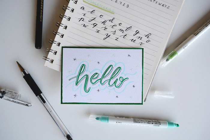 A flat lay of stationary including a notebook with the word 'hello' written on it 