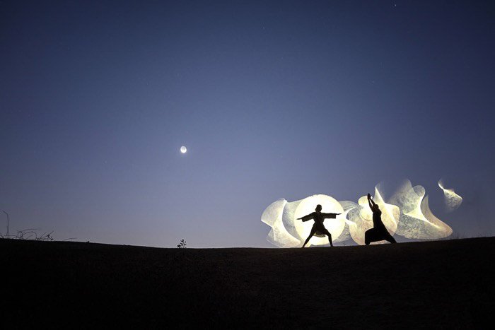 The silhouettes of two people doing creative light painting - slow shutter speed photos