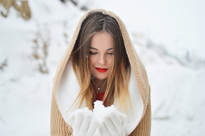 Close up winter portrait photography of a female model posing in the falling snow