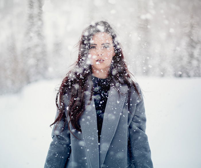 Magical winter portrait photography shot of a female model posing in the falling snow