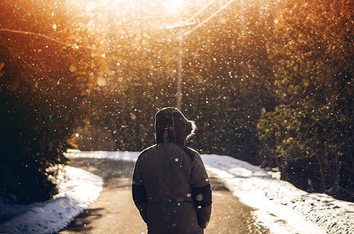 Atmospher winter portrait of a model walking down a road under falling snow