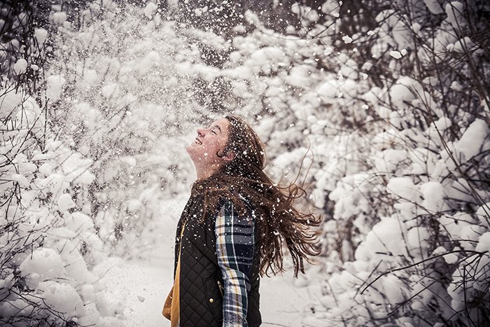 Fun snow portrait of a female model laughing and playing in the snow