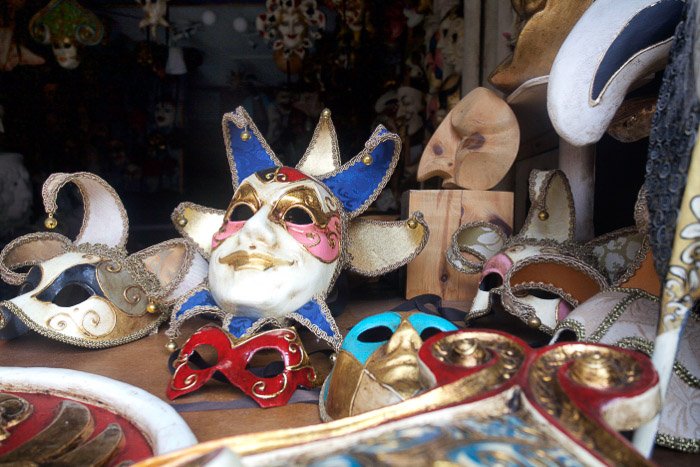 A collection of Venetian festival masks in a store window - best tips for Venice photography
