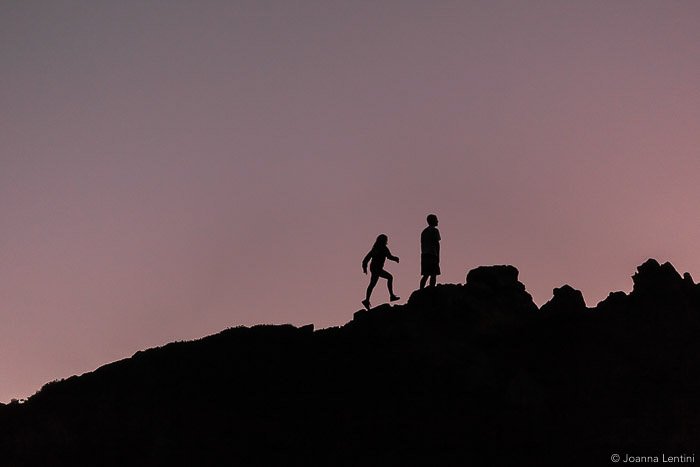 The silhouettes of two photographers walking through a landscape in low light - best wildlife clothes