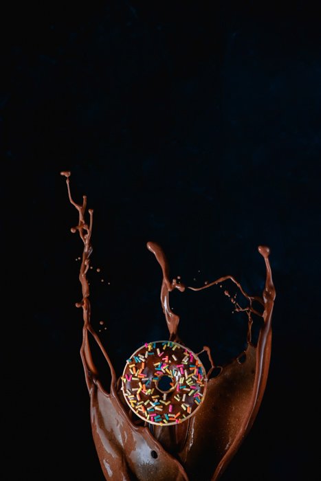 美味巧克力喷溅的前景中的巧克力甜甜圈