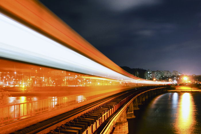 Colorful orange and white light trails moving over train tracks